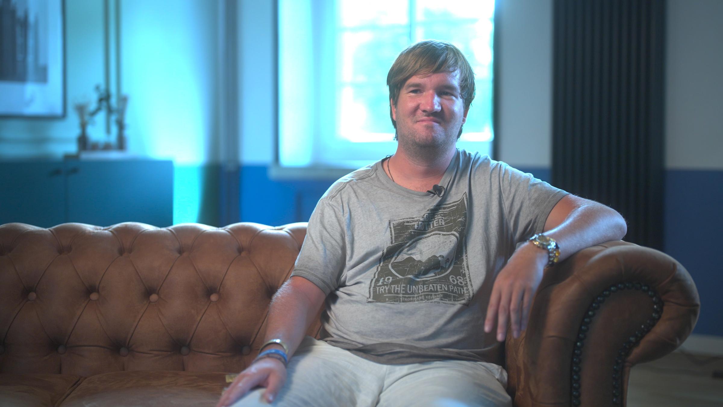 Christoph Heuermann sitzt auf einer Couch.