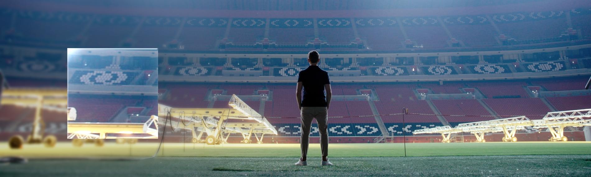 "ZDFzeit: Geheimsache Katar": Blick in ein leeres, hell beleuchtetes Fußballstadion. In der Mitte sind die dunklen Umrisse eines Menschen zu erkennen, der dem Betrachter den Rücken zukehrt