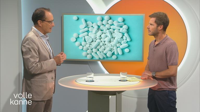 Dr. Christoph Specht bei "Volle Kanne" über chronische Schmerzen vor Bildtafel mit Tabletten