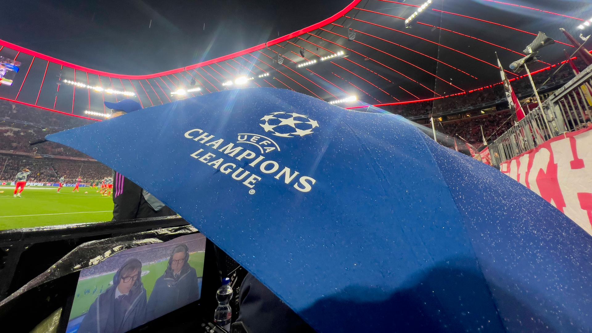 Ein Regenschirm mit dem Champions-League-Logo in der Allianz-Arena München am Spielfeldrand