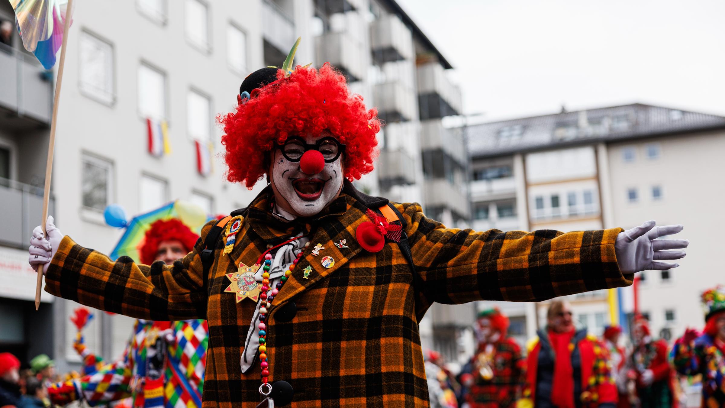 Eine als Clown verkleidete Person nimmt am Festumzug an Rosenmontag in der Mainzer Innenstadt teil.