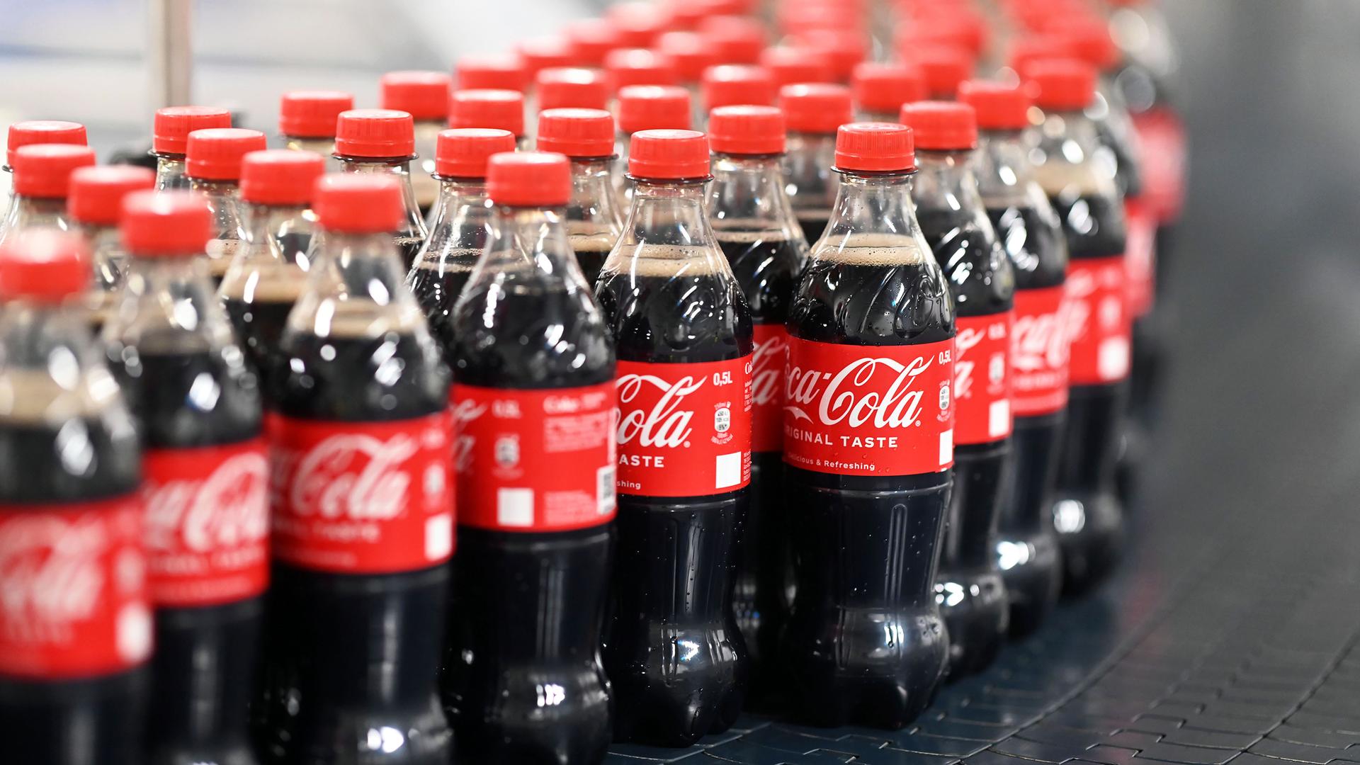 Abgefüllte 0,5 Liter Einweg Coca-Cola Flaschen werden über ein Förderband transportiert.