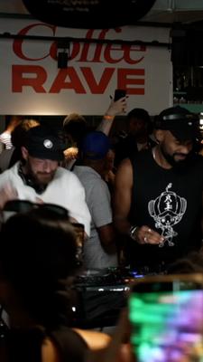 Zwei DJs ist umringt von tanzenden Menschen.