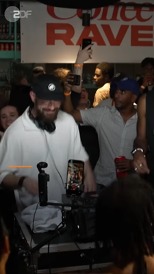 DJs legen beim Coffee Rave in Berlin vor tanzenden Menschen Musik auf. 