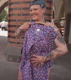 Eine Frau posiert mit einer Kittelschürze mit Blumenmuster