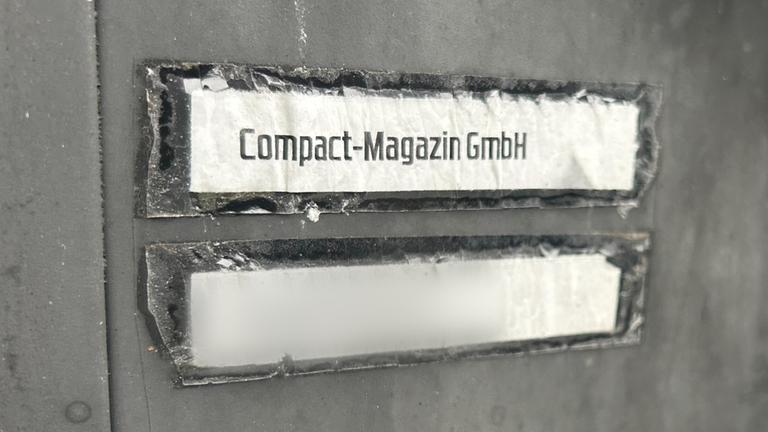 Die Aufschrift "Compact-Magazin GmbH" steht an einem Briefkasten.