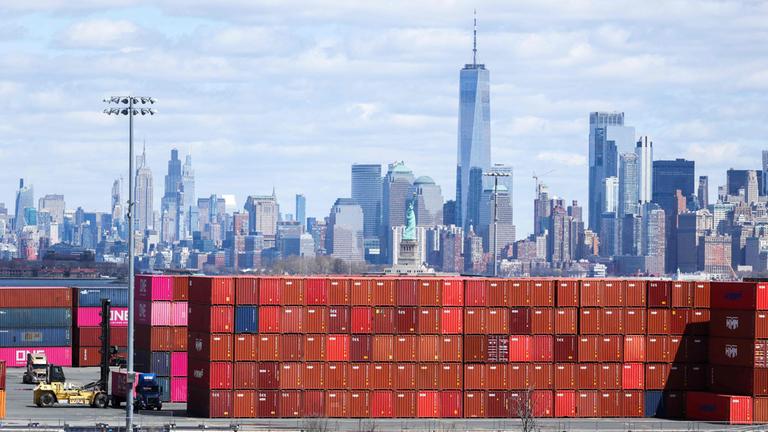 Schiffscontainer sind am 8. April 2025 am Port Jersey Container Terminal in Jersey City, mit der Skyline von Manhattan im Hintergrund.
