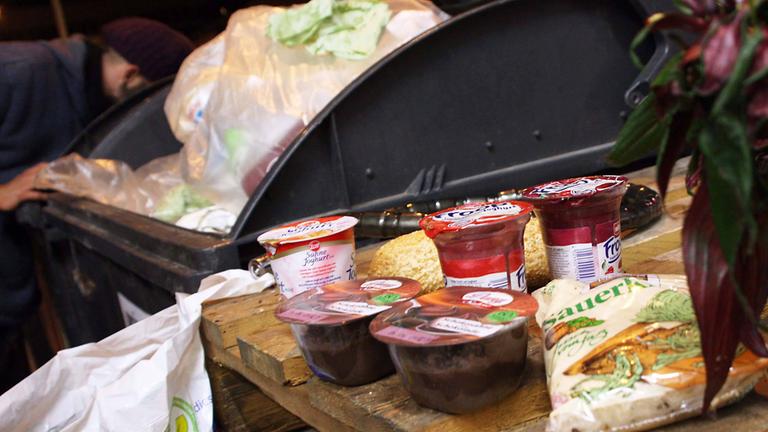 Eine Person sucht Lebensmittel in einem Müllcontainer.