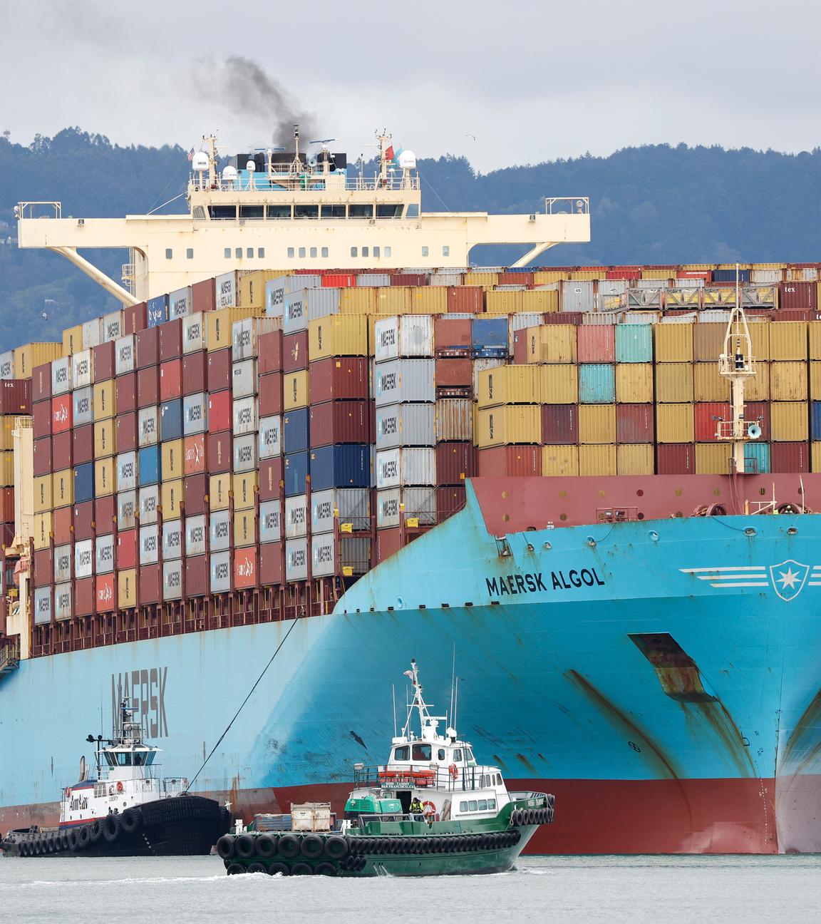 Ein Schlepper leitet ein Containerschiff im Hafen von Oakland, Kalifornien