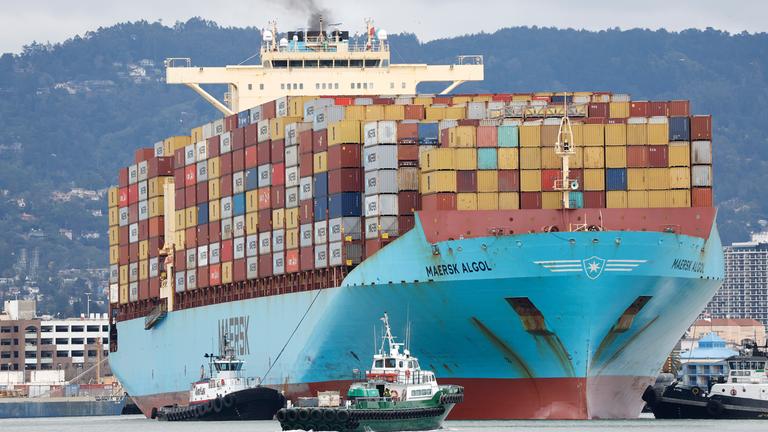 Ein Schlepper leitet ein Containerschiff im Hafen von Oakland, Kalifornien