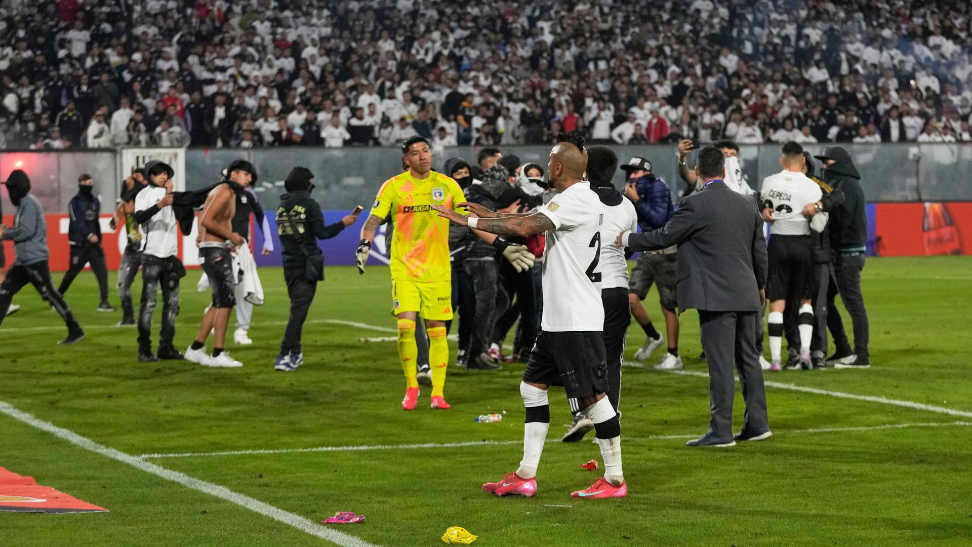 Ex-Bundesligaprofi Arturo Vidal (vorne) und andere Spieler versuchten auf den Platz gestürmte Anhänger zu beruhigen
