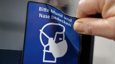 Ein Piktogramm mit dem Hinweis auf Corona-Maskenpflicht wird entfernt.