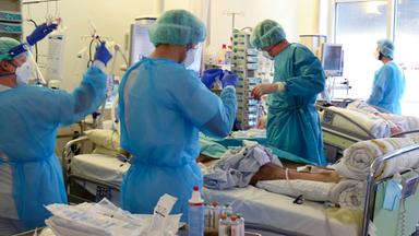 Auf der Covid-Station, einem Bereich der Operativen Intensivstation versorgen Ärzte, Schwestern und Pfleger einen Patienten.