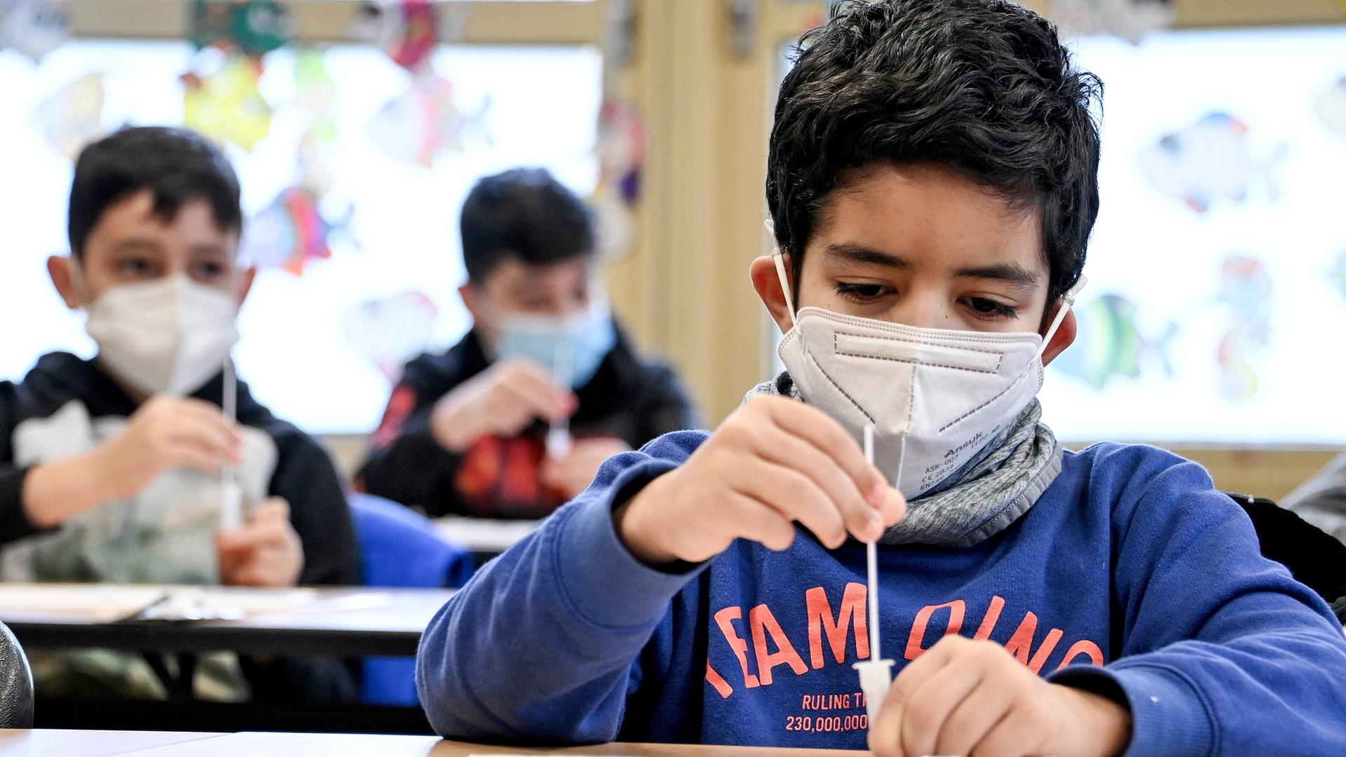 Drei Jungs im Grundschulalter, die einen Coronatest machen