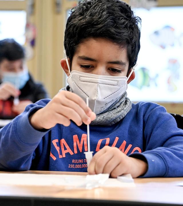 Drei Jungs im Grundschulalter, die einen Coronatest machen