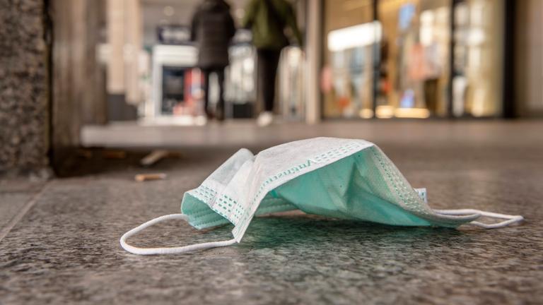 Ein weggeworfener Mundschutz liegt auf dem Boden.