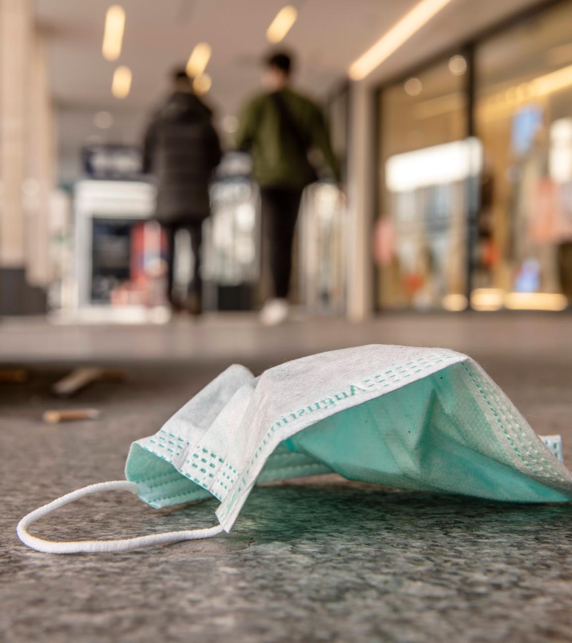 Weggeworfener Mundschutz liegt auf dem Boden