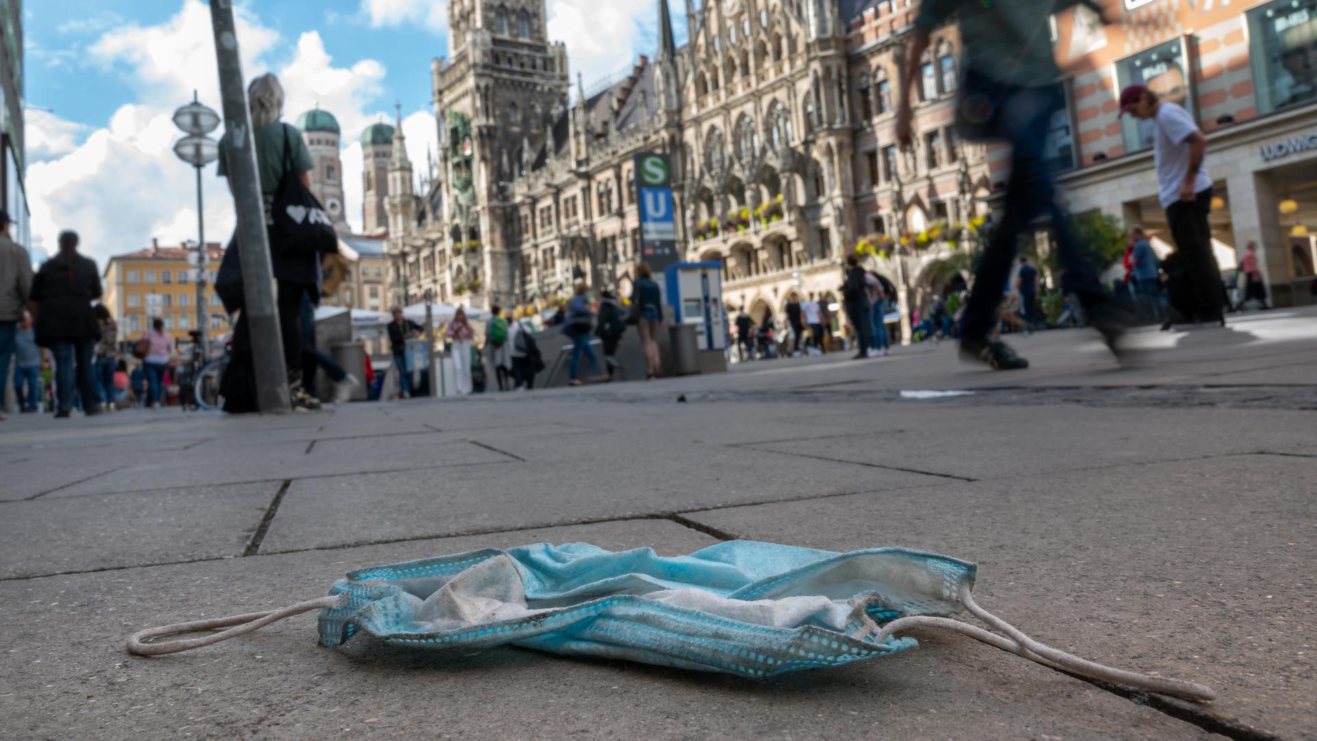 Getragene Maske liegt auf dem Boden in Fußgängerzone am Rathaus in München