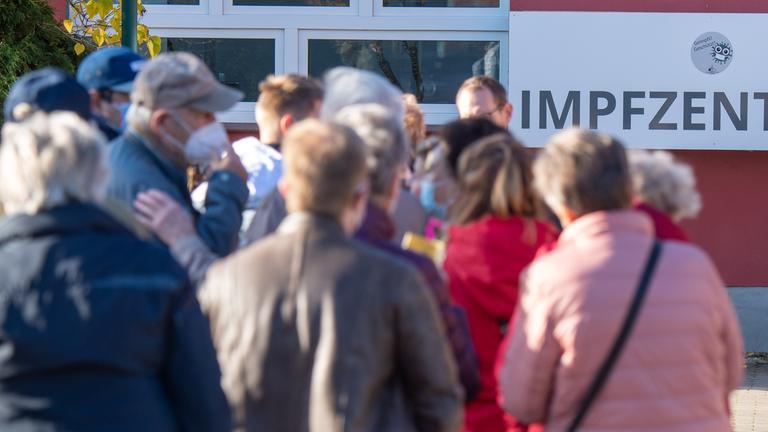 Symbolbild: Im Vordergrund warten Impflinge auf einen Termin für eine Booster-ImpfungSchild am Corona-Impfstützpunkt des Landkreis Vorpommern-Rügen in Stralsund