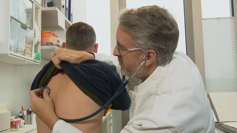 Auf dem Bild sieht man einen Arzt, der gerade einen Patienten kontrolliert.