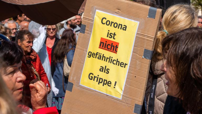 Einen Demo gegen die Corona-Maßnahmen. Das Banner: "Corona ist nicht gefährlicher als Grippe!" wird hochgehalten.