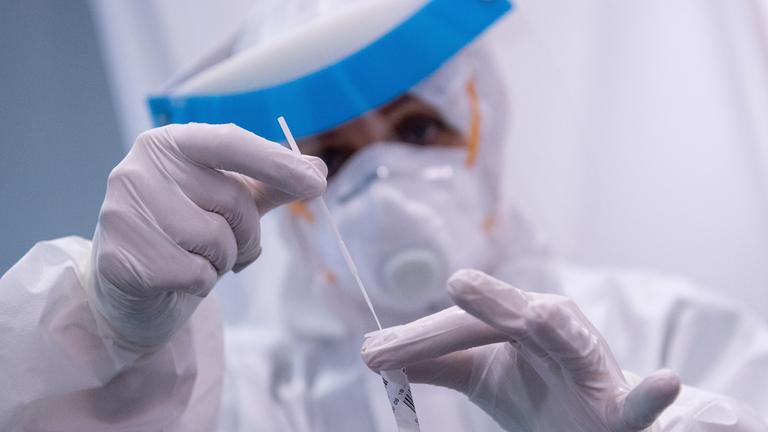 Eine Frau hält am Flughafen München in einem Covid-19 Testcenter die Probe von einem Rachenabstrich in den Händen.