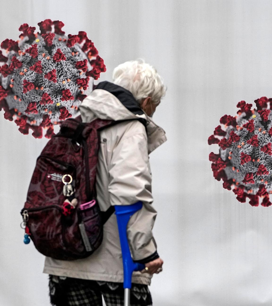 Eine ältere Frau läuft an einem Testcontainer mit Coronavirus-Aufklebern vorbei.