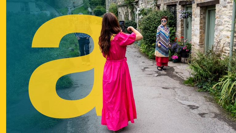 Eine Frau fotografiert eine andere Frau vor einem alten schönen englischen Cottage