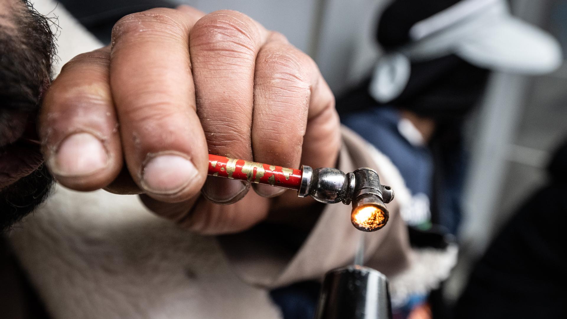 Drogenabhängige Person raucht eine Crackpfeife.