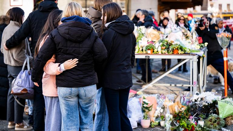 2.01.2026, Schweiz, Crans-Montana: Menschen erweisen den Opfern der Silvesterfeier in Crans-Montana, Schweiz, mit Blumen die letzte Ehre.