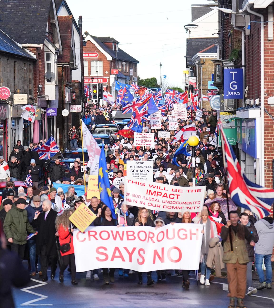 Menschen gehen bei einer Anti-Einwanderungsdemonstration im Zentrum von Crowborough, East Sussex mit Plakaten durch die Stadt.