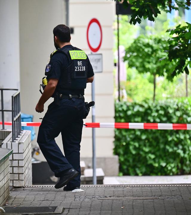 Ein Polizeibeamter geht an den Wohnblöcken vorbei, in denen  in der Nacht eine Wohnung durchsucht wurde. 