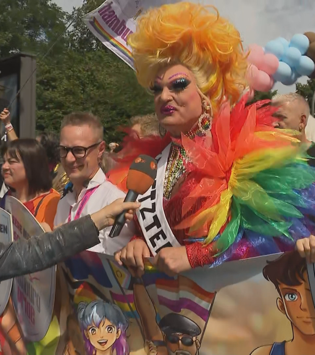 ZDF-Reporterin Petra Meier interviewt Dragqueen Olivia Jones auf dem Hamburger CSD. Olivia Jones trägt ein Outfit in Regenbogenfarben.
