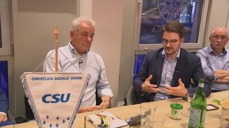 Mitglieder der CSU in Dillingen sitzen an einem Tisch in einer Gaststätte, im Vordergrund steht ein Wimpel mit der Aufschrift "CSU"