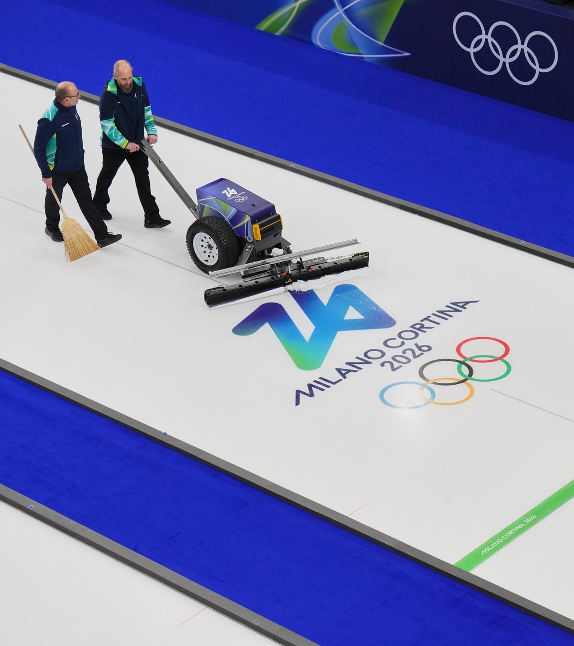 Zwei Männer präparieren die Curling-Bahn vor den Olympischen Winterspielen 2026