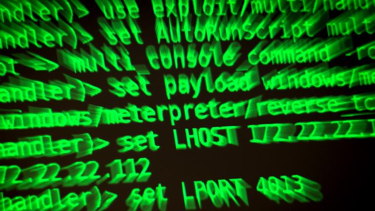 Buchstaben und Zahlen leuchten auf einem Bildschirm, auf dem ein Hacker-Programm geöffnet ist