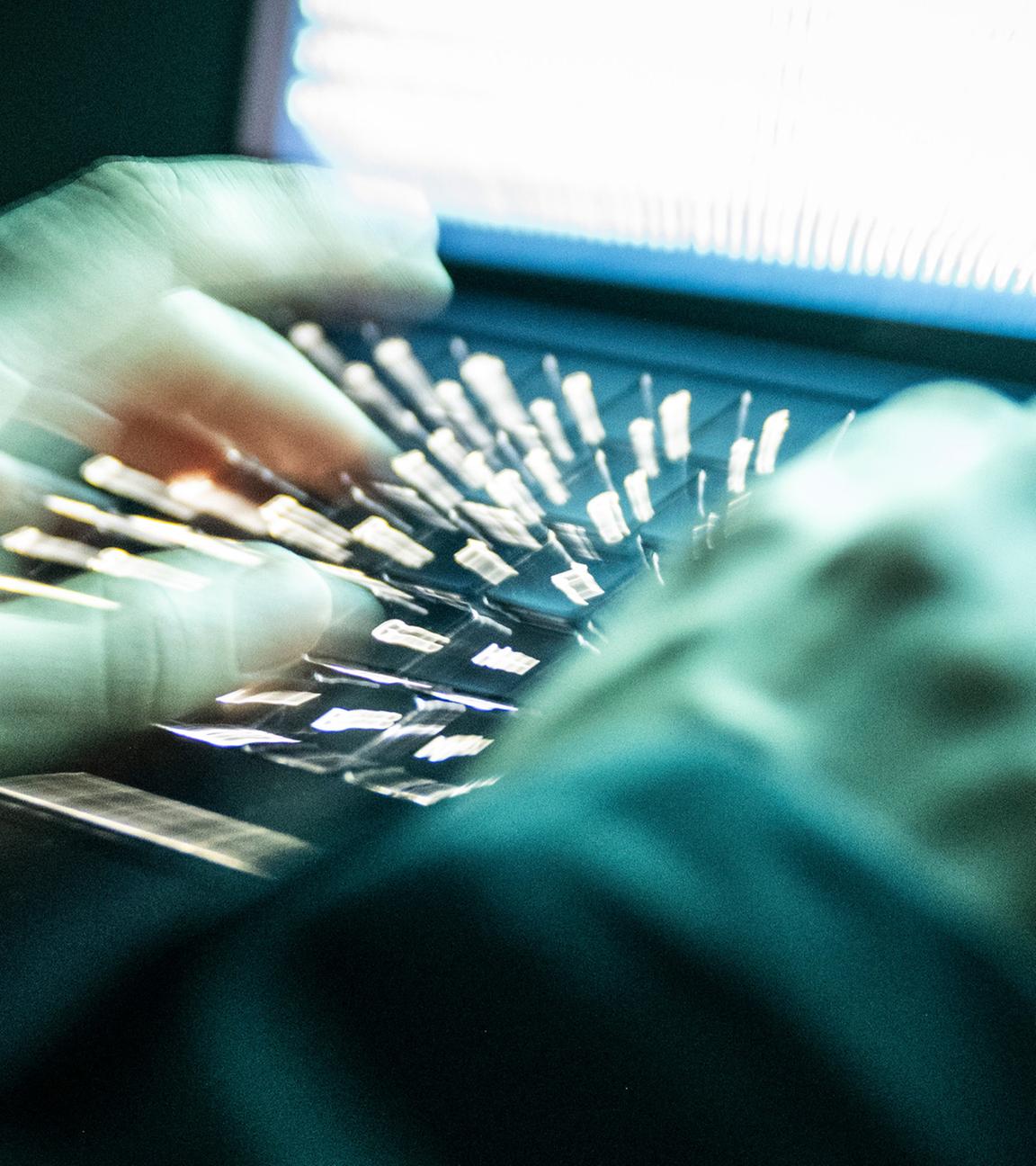 Eine Person tippt mit den Fingern auf einer beleuchteten Laptop-Tastatur. (Symbolbild)