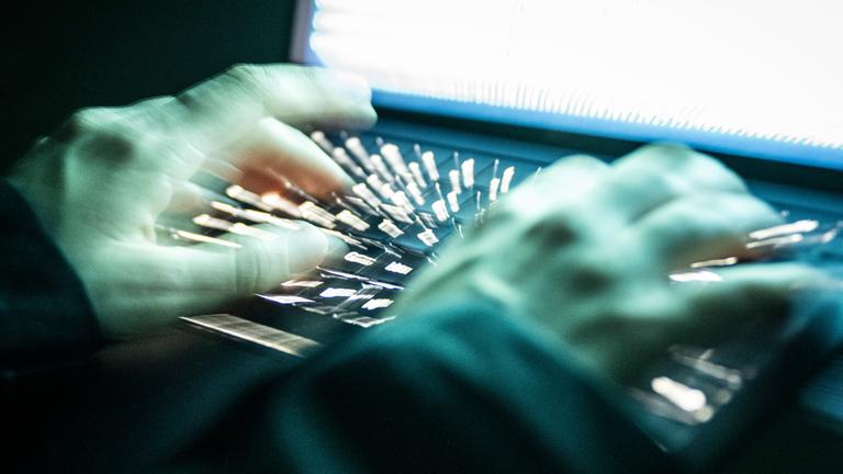 Eine Person tippt mit den Fingern auf einer beleuchteten Laptop-Tastatur. (Symbolbild)