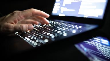 ILLUSTRATION - 14.12.2025, NA, Berlin: Eine Person tippt mit den Fingern auf einer beleuchteten Laptop-Tastatur. (gestellte Szene) (zu dpa: «Cyberangriff auf Verwaltung  Untersuchungen laufen weiter»)