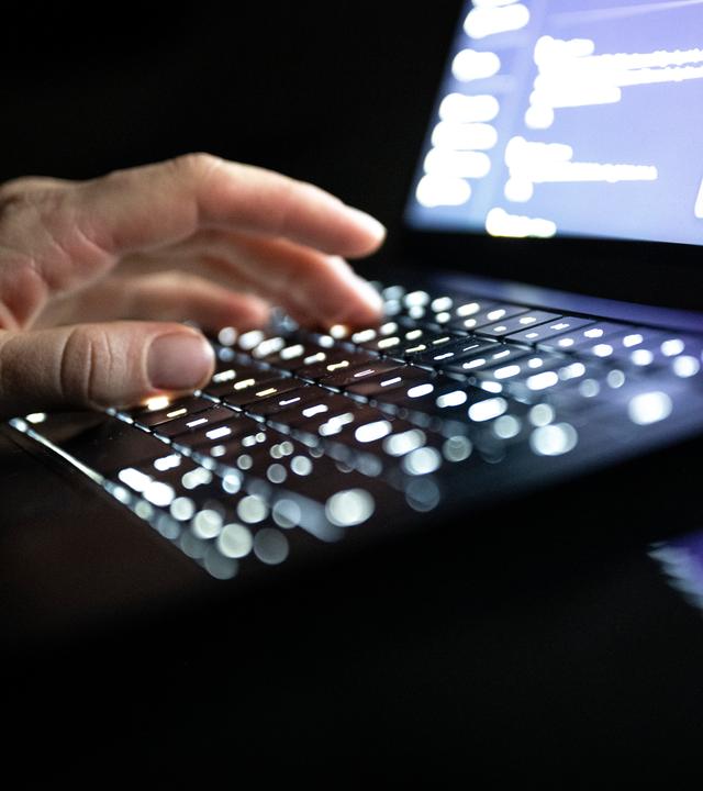 ILLUSTRATION - 14.12.2025, NA, Berlin: Eine Person tippt mit den Fingern auf einer beleuchteten Laptop-Tastatur. (gestellte Szene) (zu dpa: «Cyberangriff auf Verwaltung  Untersuchungen laufen weiter»)