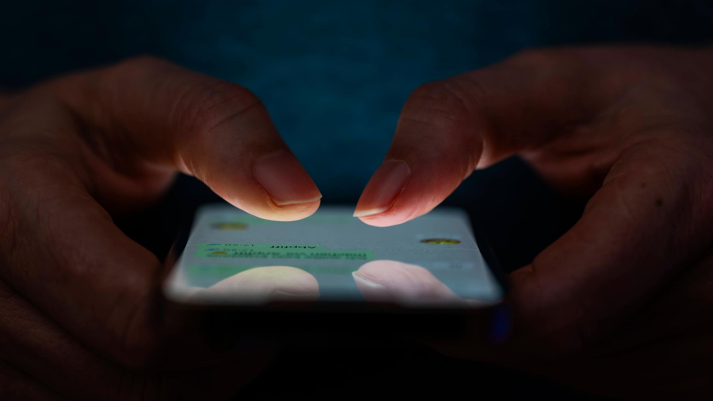 Frau tippt auf einem Apple iPhone13 Smartphone-Screen SMS.