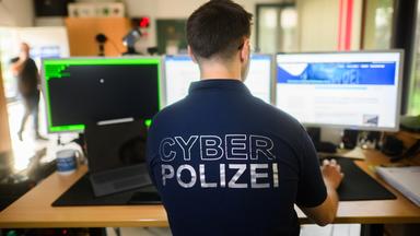 Niedersachsen, Hannover: Ein Polizist steht mit einem Poloshirt mit Aufschrift Cyber Polizei an einem Computer in der Präventionsstelle Cyberkriminalität im Landeskriminalamt Niedersachsen (Symbolbild für Cybersicherheit).