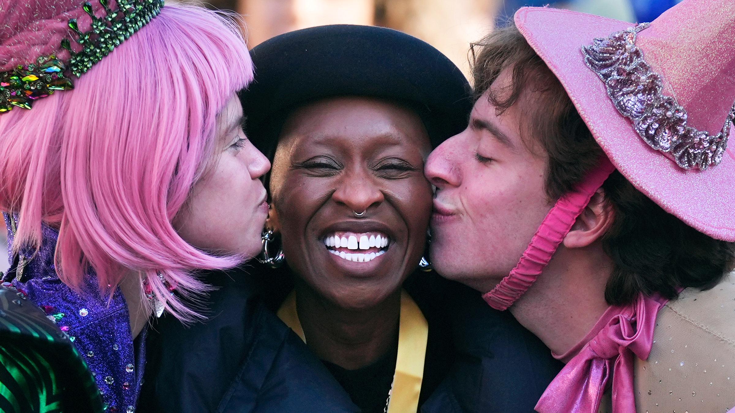 Zwei Personen geben Cynthia Erivo von links und rechts ein Küsschen auf die Wange.