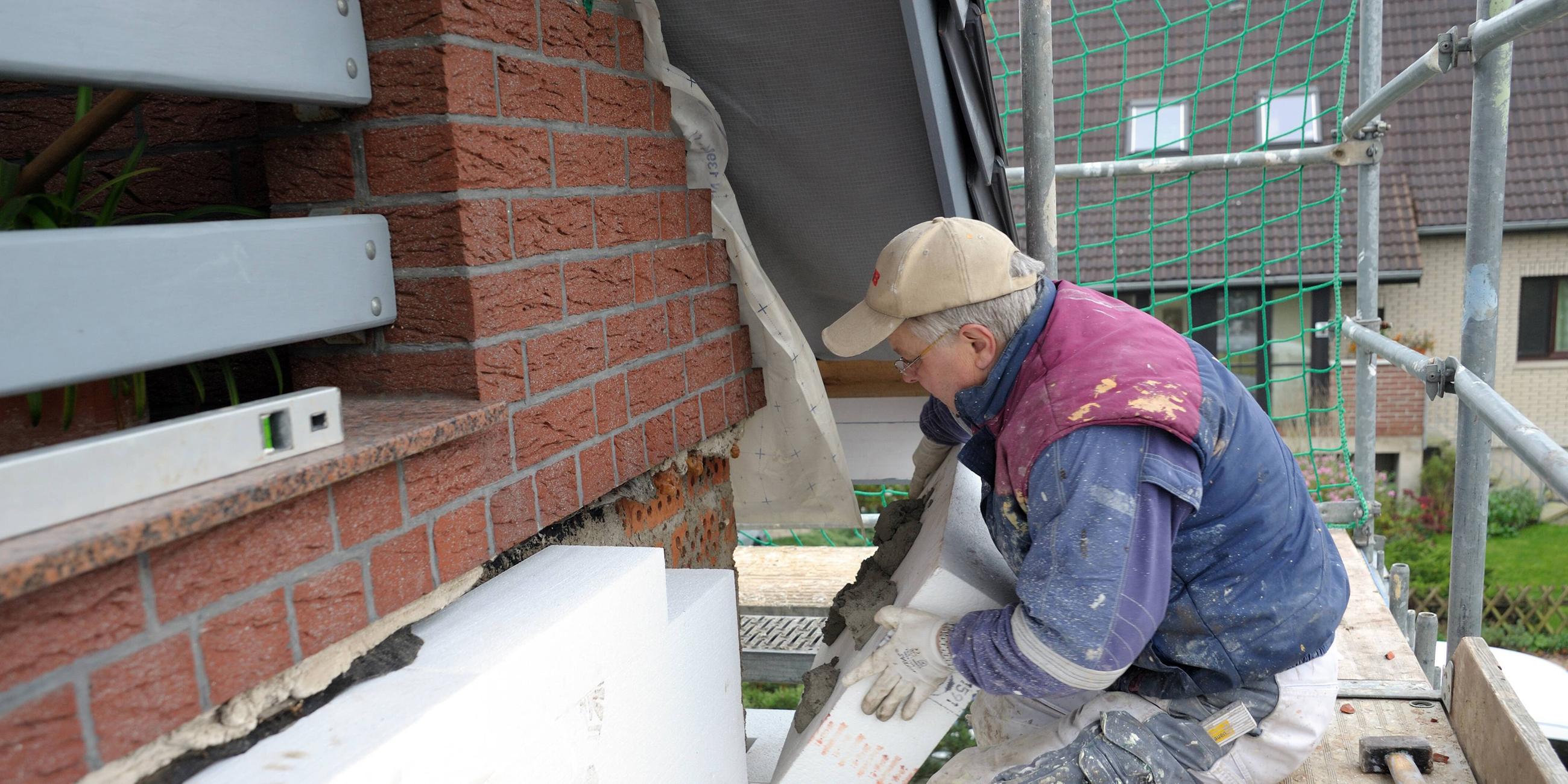 Maler klebt Fassadendämmplatten an ein Haus