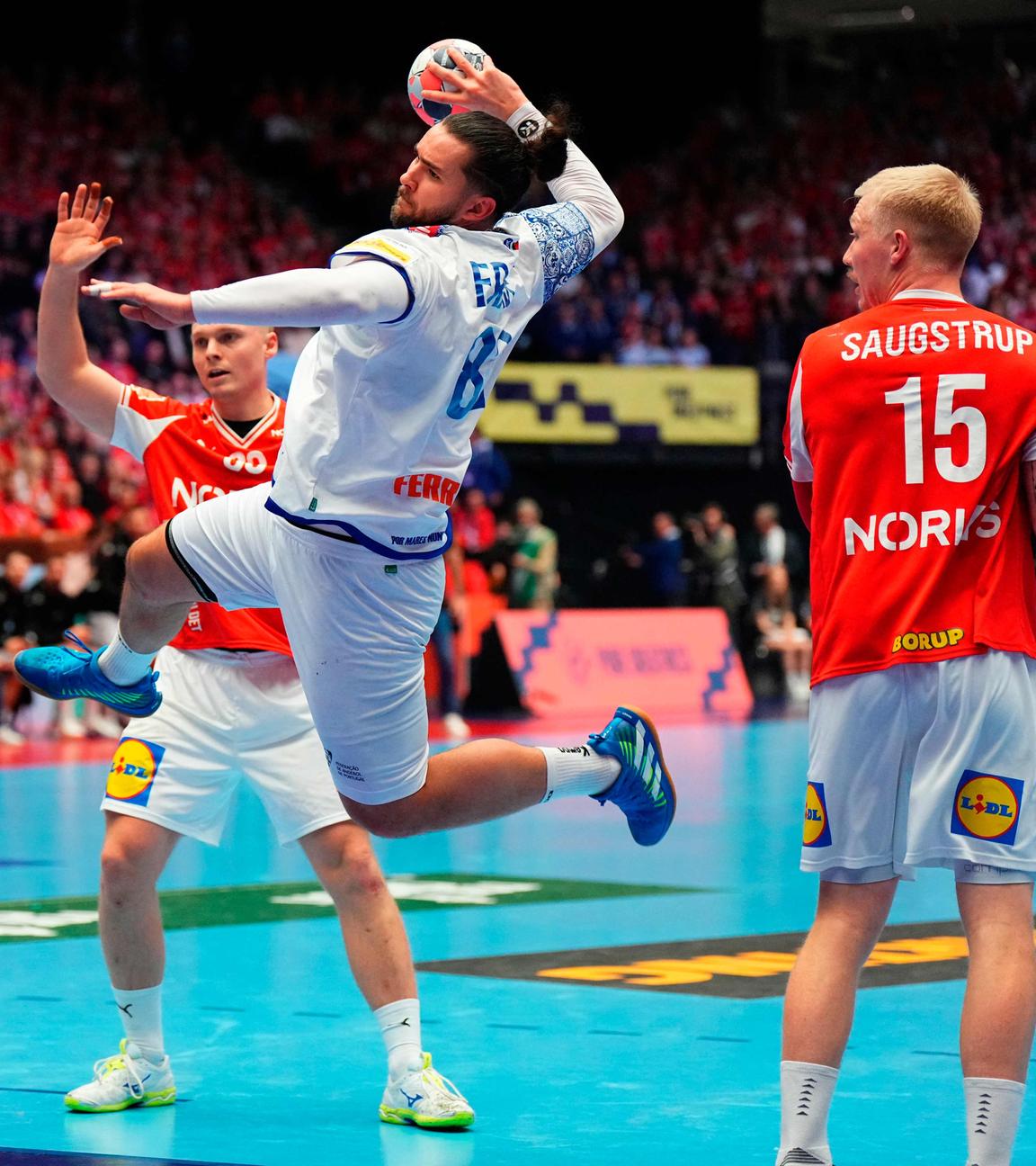 Mathias Gidsel beim Sprungwurf aus dem Rückraum. Leonel Fernandes und Victor Iturriza behindern ihn.