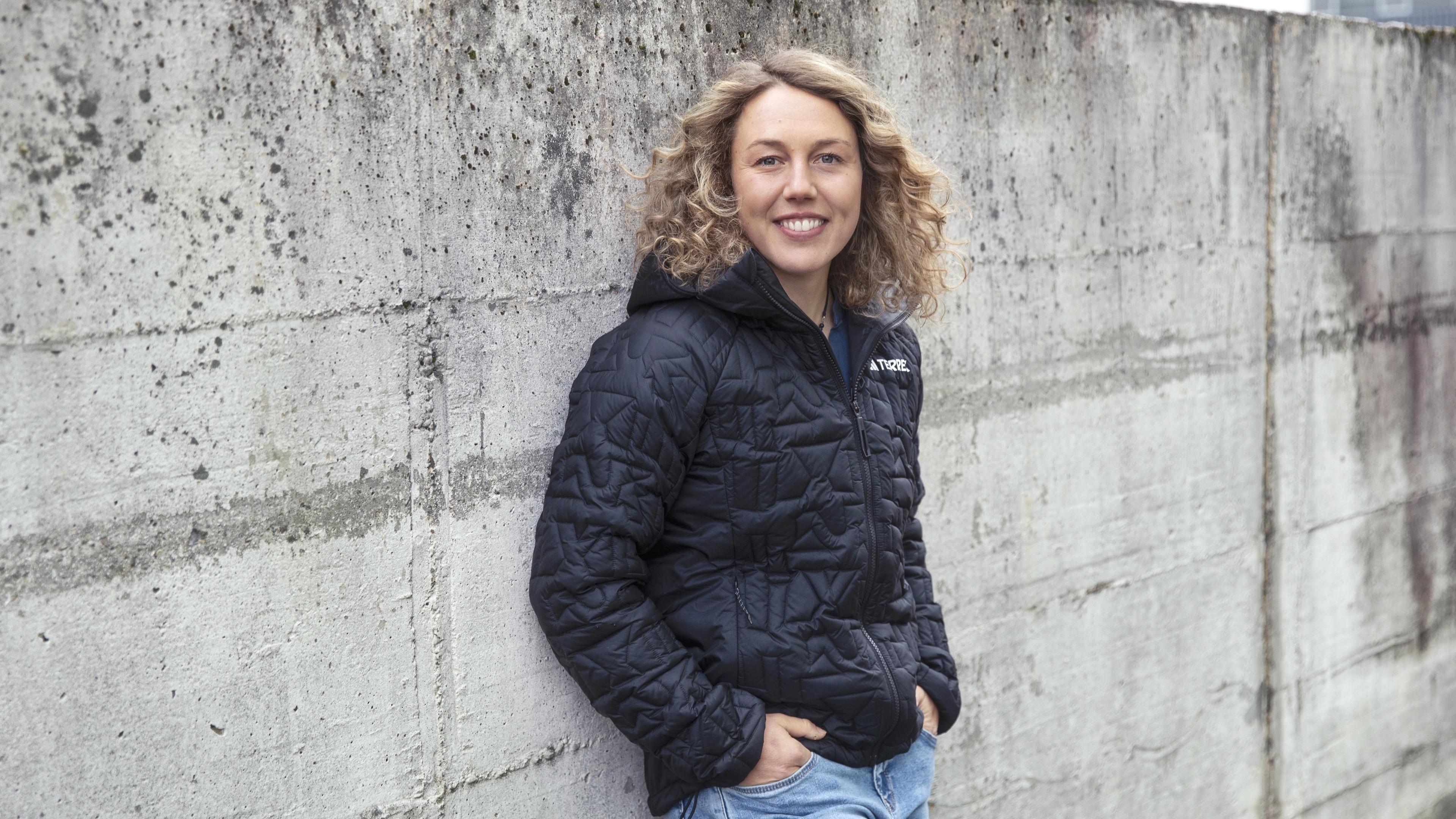 Laura Dahlmeier Laura Dahlmeier lehnt an einer grauen Mauer und lächelt in die Kamera. 