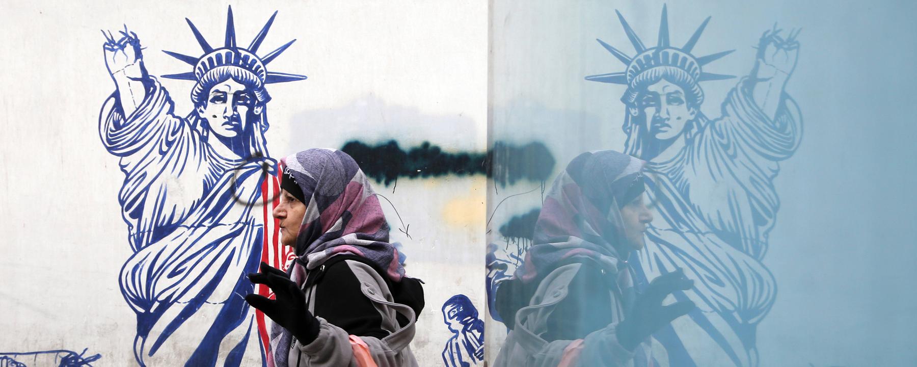 Ältere Frau geht am 28. Januar 2026 in Teheran an einem anti‑amerikanischen Wandbild vorbei