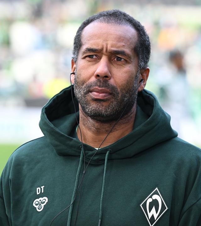 Daniel Thioune steht auf einem Fußballfeld.