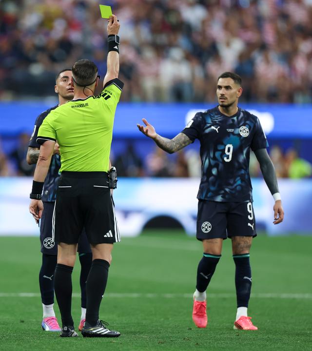 Schiedsrichter Danny Makkelie (vorn) zeigt dem paraguayischen Spieler Miguel Almiron (hunten) die Gelbe Karte.