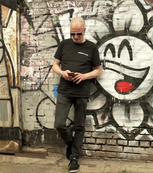 Daniel Rau lehnt an Wand mit Graffiti